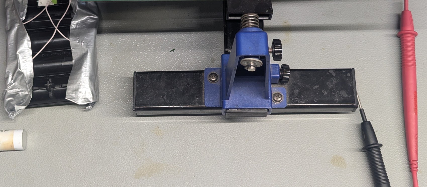 A close view of the test rig on the bench: a board held in a clamp with probes and a wire harness attached